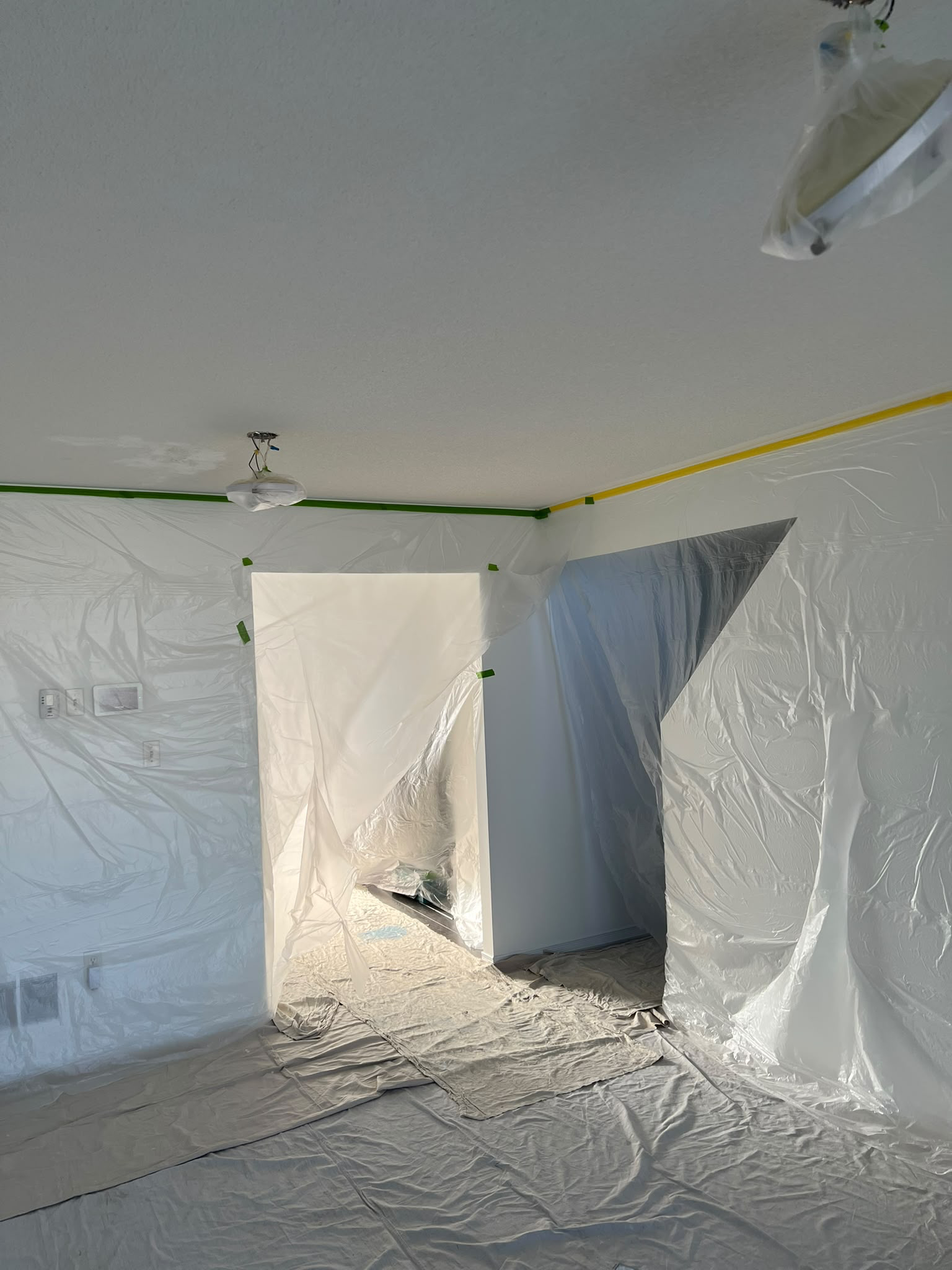 Work area isolated with protective sheeting over walls and doorways, covered fixtures and floor protection
